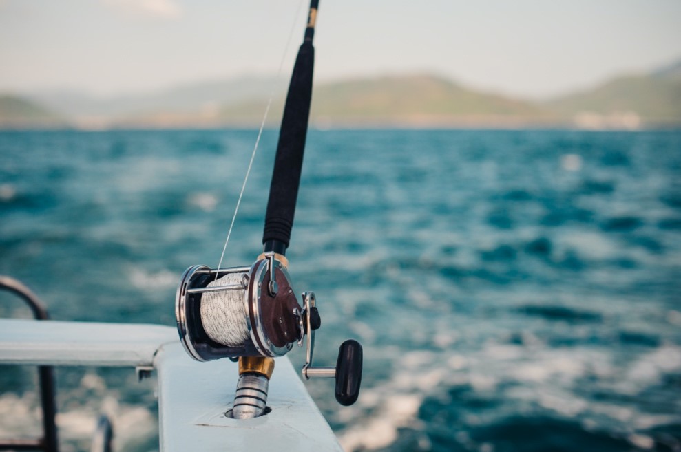 A fishing rod and reel on the side of a boat.