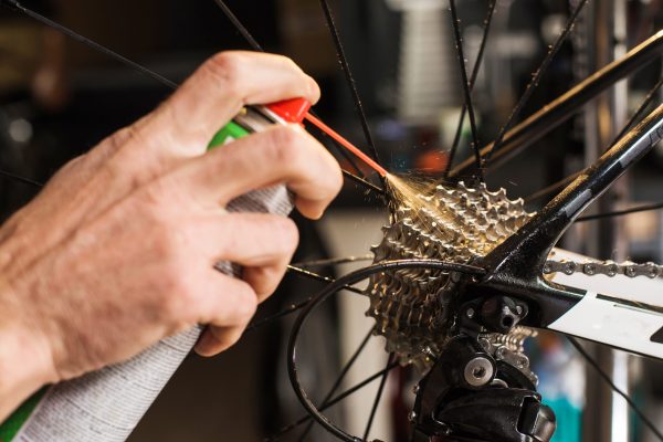 A person is using a spray gun to fix the spokes on a bicycle.