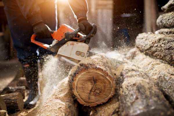 A person using a chain saw to cut wood.