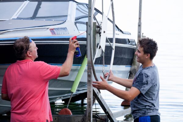 Two men are washing a boat in the water.