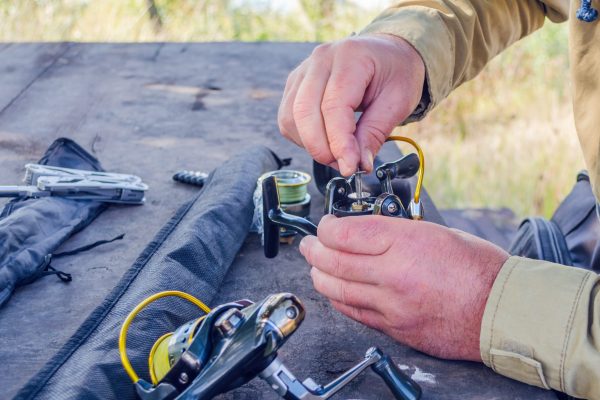 A man is fixing the wire on his fishing rod.