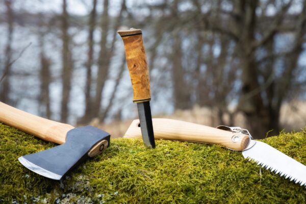 A pair of knives and an axe on the ground.