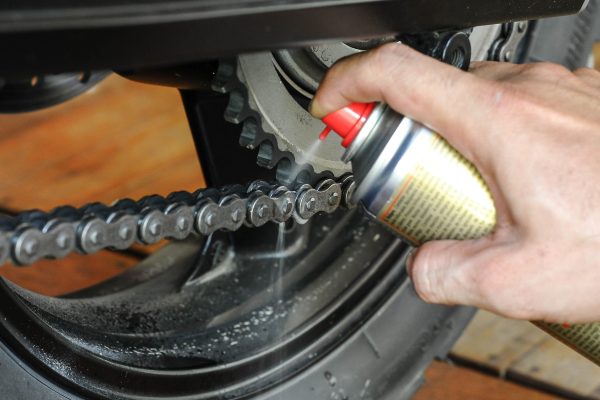 A person is using a spray gun to clean the chain.