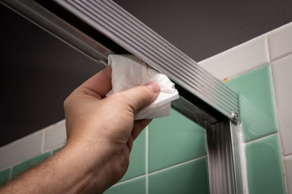 A person holding paper towels in front of a shower door.