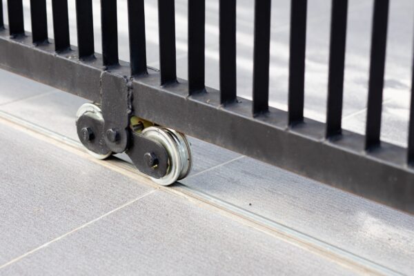 A roller is attached to the side of a fence.