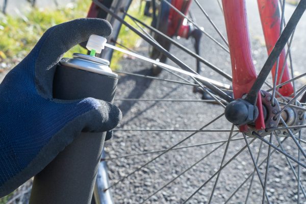 A person is using a spray gun to fix the spokes on their bike.