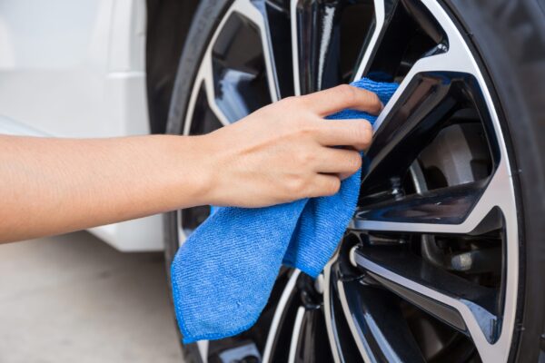 A person cleaning the wheels of their car