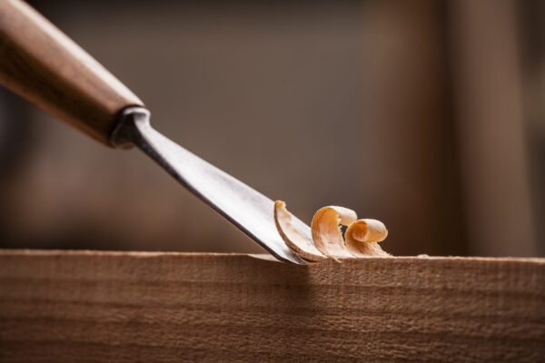 A knife cutting through wood with an orange peel.